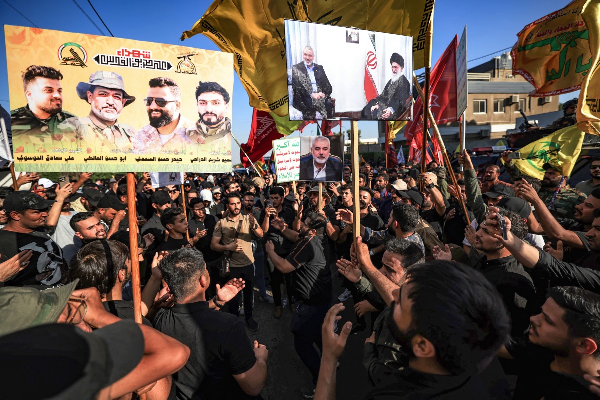 Supporters of Iraq's Hashed al-Shaabi raise a placard bearing the pictures of four members of the Hashed killed in a US air strike south of Baghdad as well as pictures of slain political leader of Hamas Ismail Haniyeh, during a march in the Iraqi capital to condemn the killings, on July 31, 2024.(AFP)
