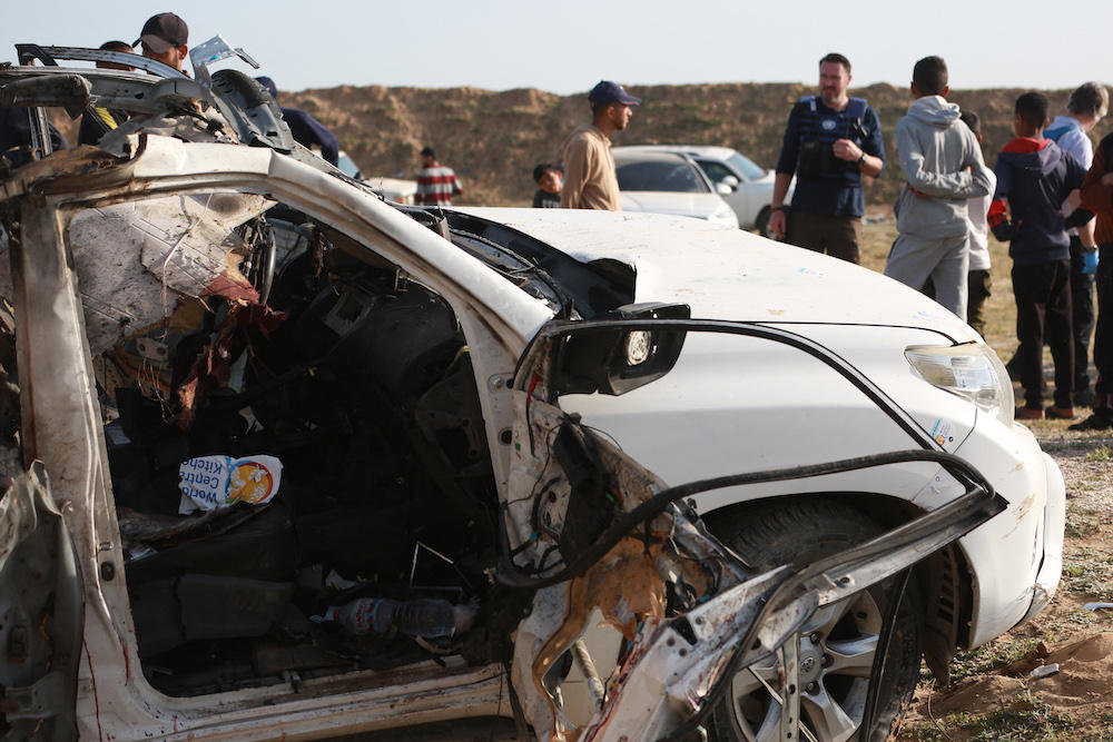 People gather around the carcass of a car used by aid group World Central Kitchen, which was hit by an Israeli strike the previous day, in Deir Al-Balah in the central Gaza Strip on April 2, 2024. (AFP)
