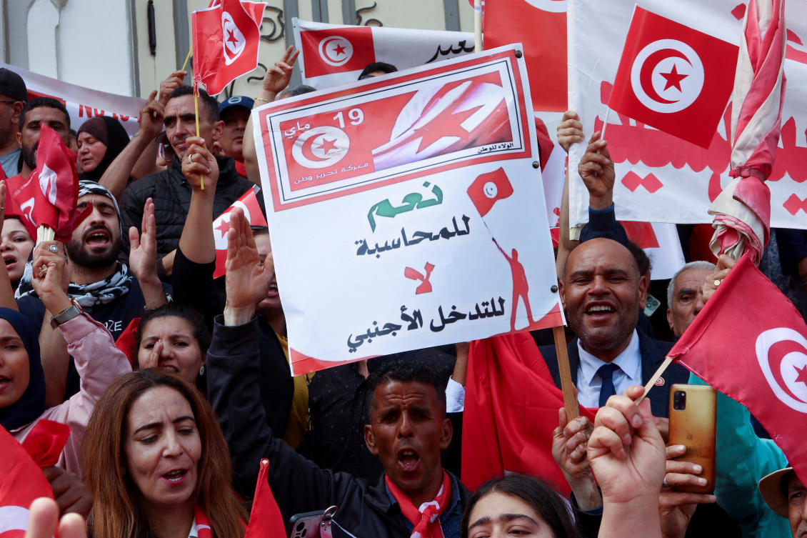 Supporters of Tunisian President Kais Saied carry flags and signs during a demonstration to show their support for him and to reject what they say is "foreign interference", in Tunis, Tunisia. (File/Reuters)
