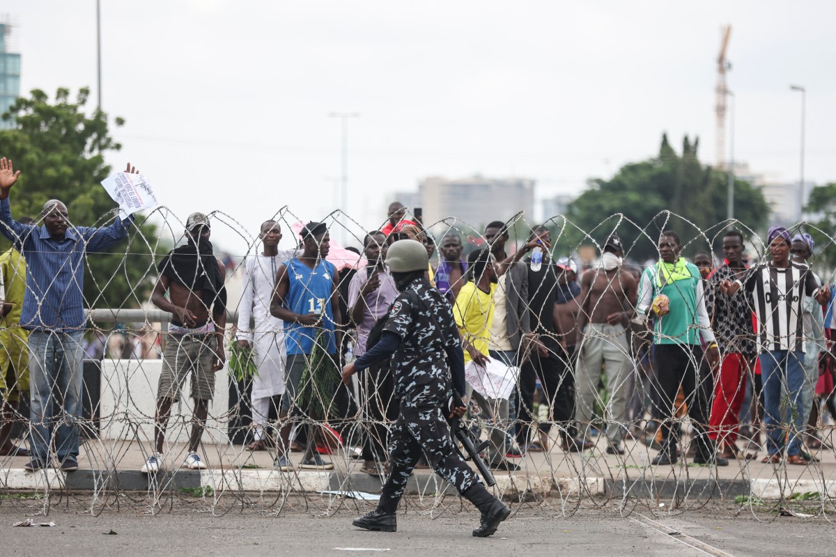 A member of Nigerian security forces walks in front of protestors during the End Bad Governance protest in Abuja on August 1, 2024. (AFP)