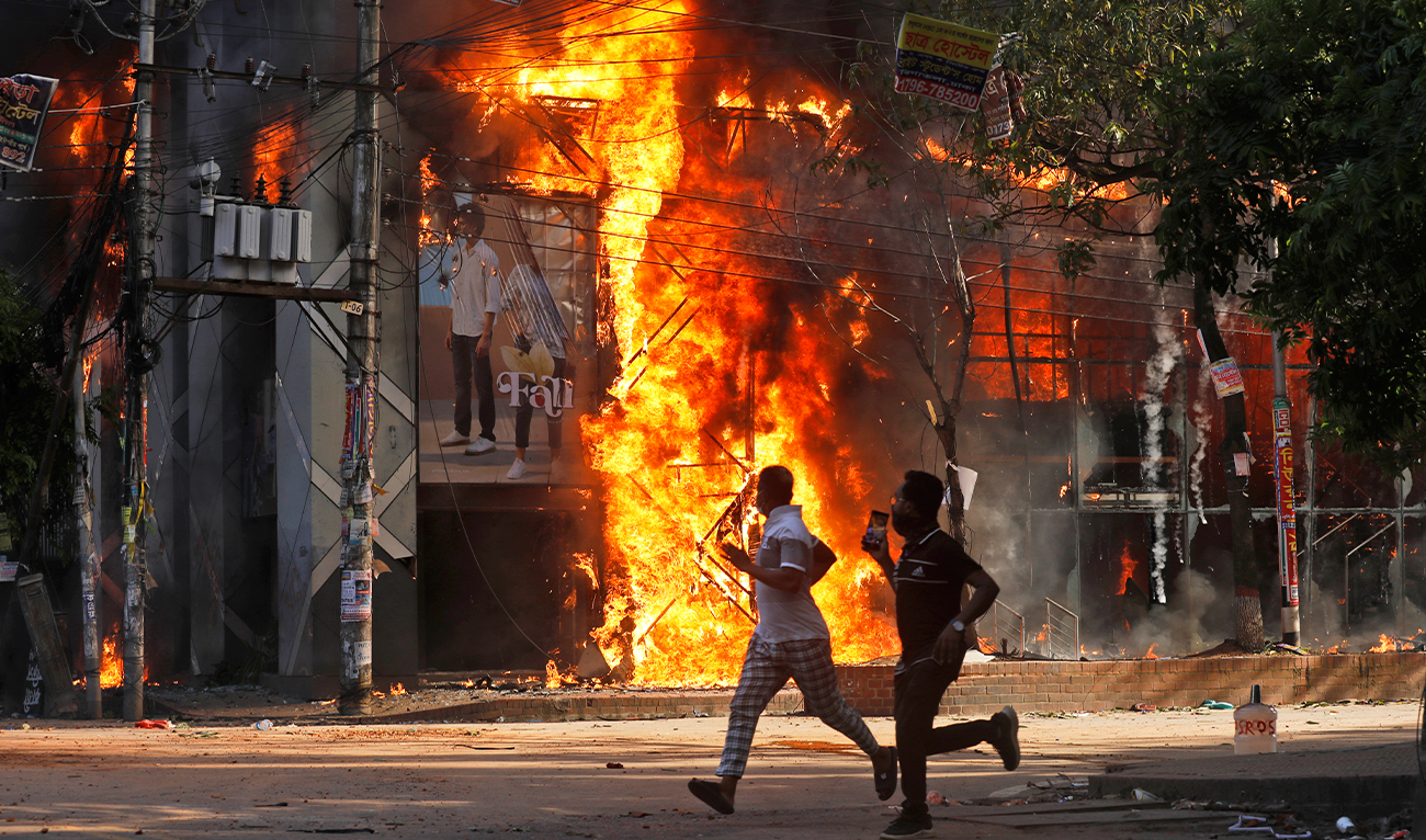 Men run past a shopping center which was set on fire by protesters during a rally against Prime Minister Sheikh Hasina and her government demanding justice for the victims killed in the recent countrywide deadly clashes, in Dhaka, Bangladesh, on August 4, 2024. (AP)