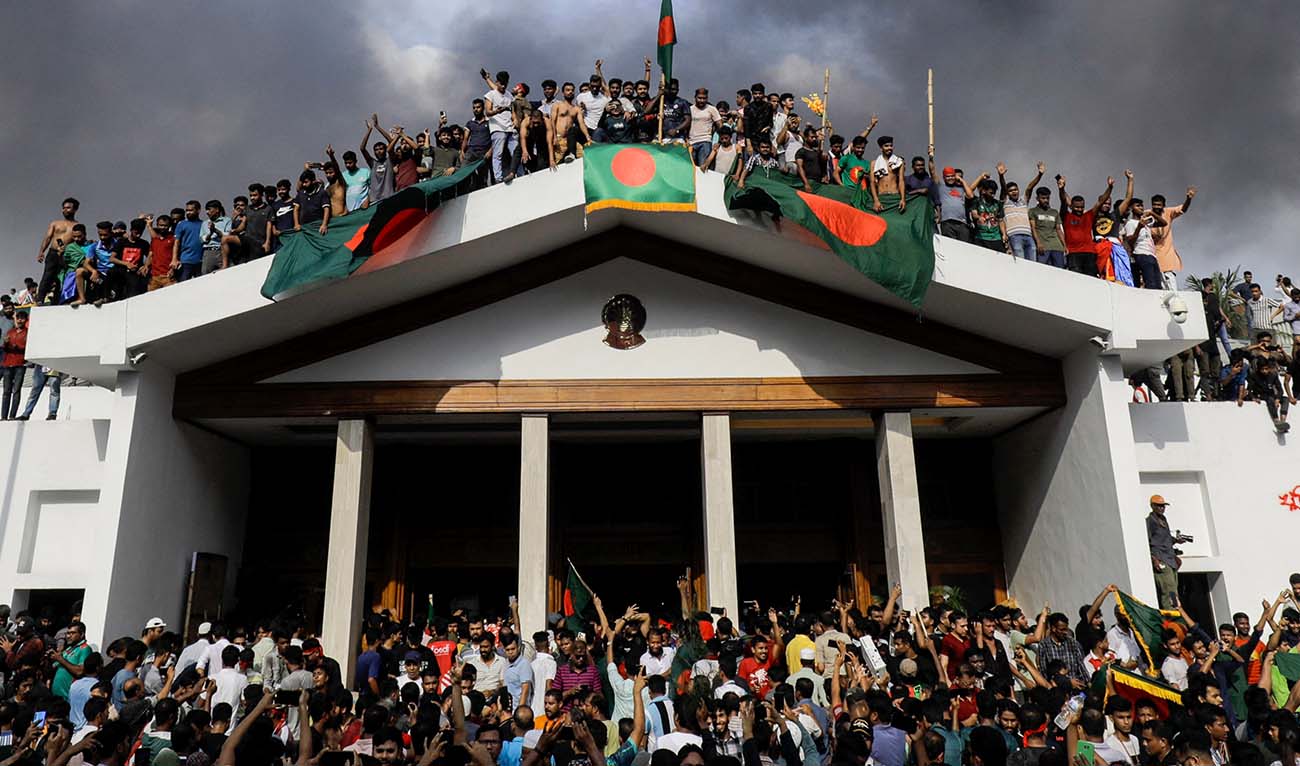 Anti-government protestors display Bangladesh's national flag as they storm Prime Minister Sheikh Hasina's palace in Dhaka on August 5, 2024. (AFP)