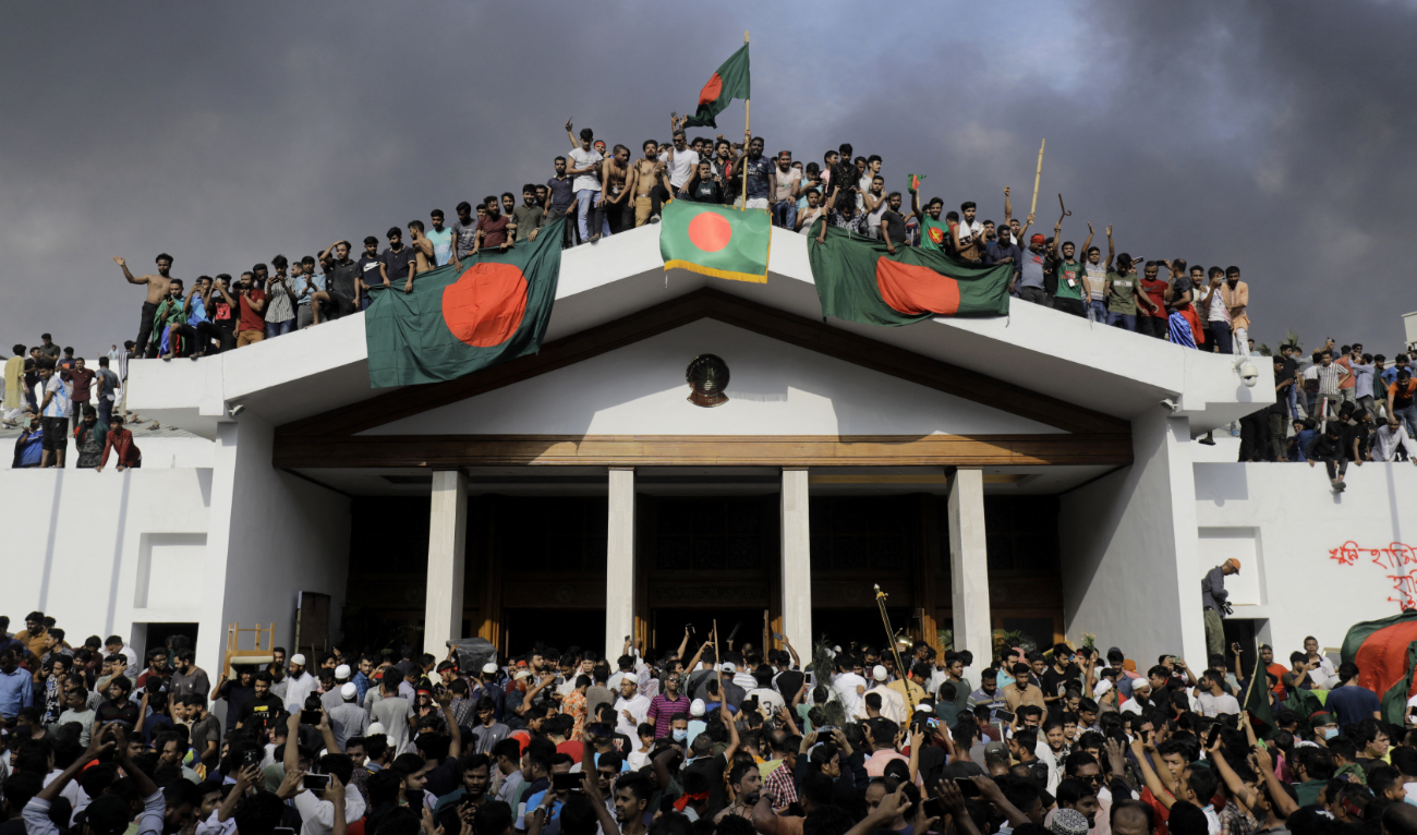 Anti-government protestors display Bangladesh's national flag as they storm Prime Minister Sheikh Hasina's palace in Dhaka on August 5, 2024. (AFP)