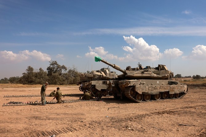 Israeli soldiers work on their tanks in an army camp near Israel's border with the Gaza Strip (AFP/File Photo)
