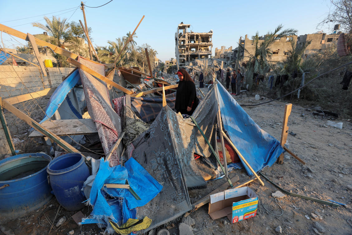 A Palestinian woman inspects a tent damaged in an Israeli strike, amid the Israel-Hamas conflict, in Deir Al-Balah in the central Gaza Strip, August 7, 2024. (Reuters)