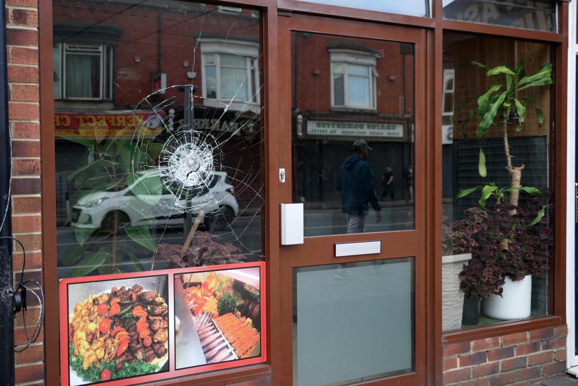A broken glass window is pictured at a take-away food shop in Middlesbrough, north east england following rioting and looting the day before. (AFP)