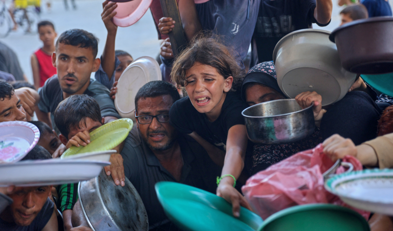Displaced Palestinians wait to receive for food at a food distribution point, set up by young men from the Madhoun family in Beit Lahia, in the northern Gaza Strip on July 18, 2024. (AFP)