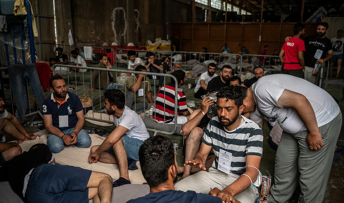 Survivors of a shipwreck sit inside a warehouse at the port in Kalamata town, on June 15, 2023, after a boat carrying migrants sank in international waters in the Ionian Sea. (AFP/File)
