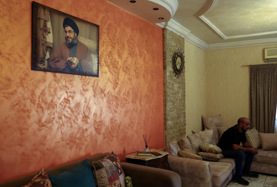 Bilal Sahlab, 45, sits near a picture depicting Hezbollah leader Sayyed Hassan Nasrallah inside his home in Dahiyeh, Beirut suburbs, Lebanon August 8, 2024. (REUTERS)