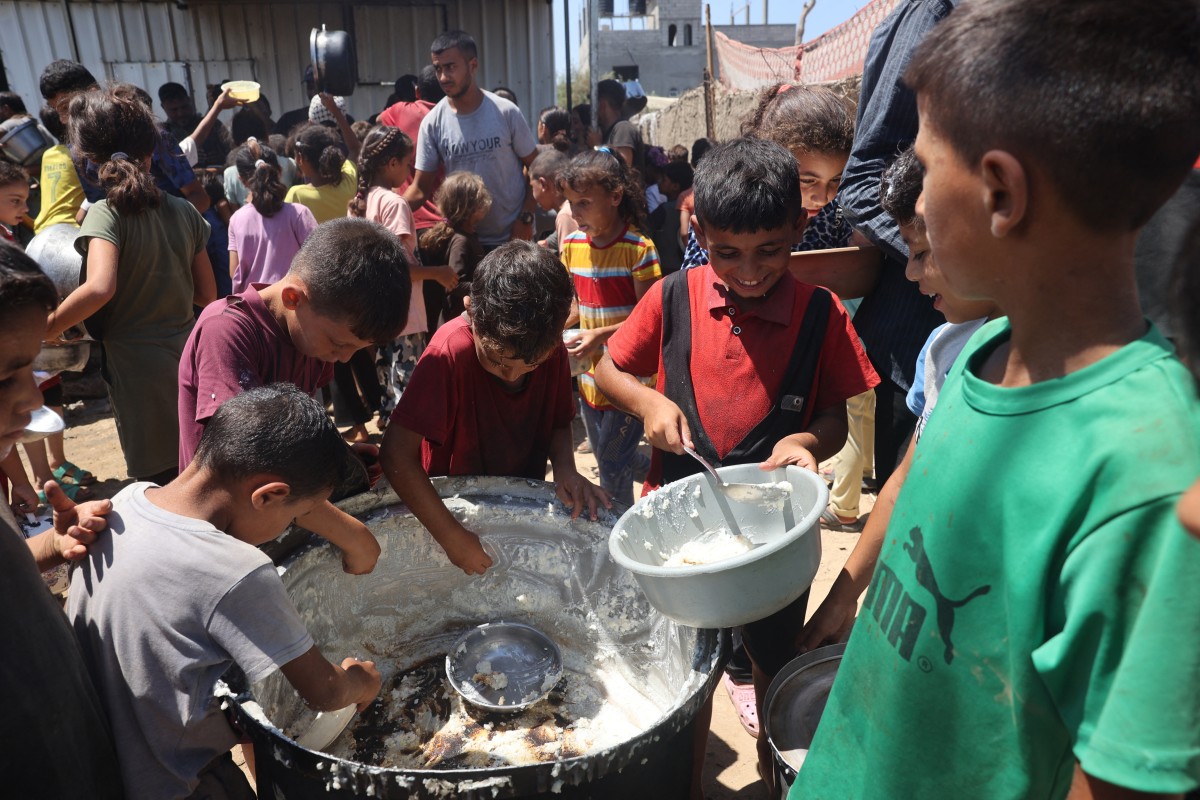 Palestinian children scrape the food remaining in the bottom of a pan at a distribution point in Deir el-Balah in the central Gaza Strip on August 8, 2024, amid the ongoing conflict between Israel and the Palestinian militant group Hamas.(AFP)