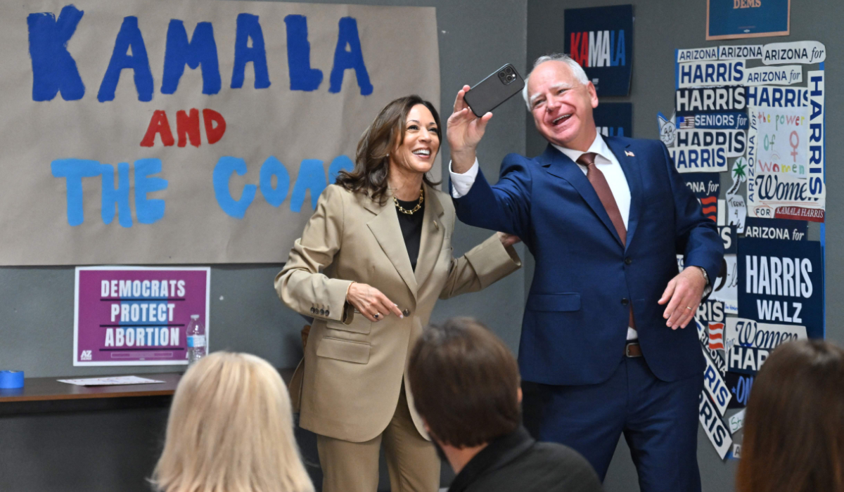 US Vice President and 2024 Democratic presidential candidate Kamala Harris and Minnesota Governor and 2024 Democratic vice presidential candidate Tim Walz take a selfie in front of the "Kamala and the Coach" sign on the wall as they visit a local campaign office in Phoenix, Arizona, on August 9, 2024. (AFP)