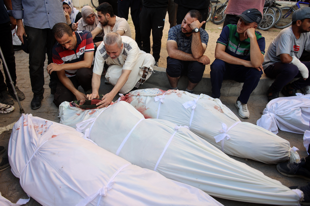 People mourn over the shrouded body of a family memberfollowing an Israeli strike that killed more than 90 people on a school sheltering displaced Palestinians in Gaza on August 10, 2024. (File/AFP)