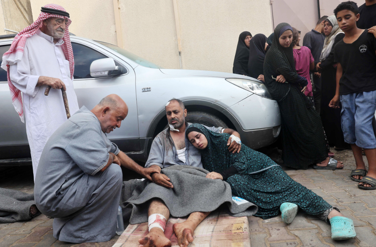 An injured man comforts his daughter after several members of his family were killed in an overnight Israeli strike that hit the family home in Nuseirat, in front of the Al-Aqsa Martyrs hospital in Deir el-Balah in the central Gaza Strip on August 10, 2024, amid the ongoing conflict between Israel and the Palestinian Hamas movement. (AFP)