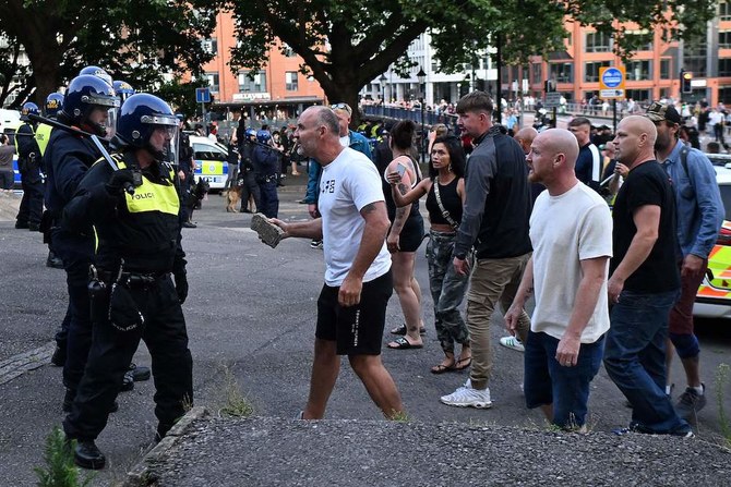 A protester holding a piece of concrete walks towards riot police as clashes erupt in Bristol on Aug. 3, 2024 during a demonstration held in reaction to the fatal stabbings in Southport on July 29. (AFP)