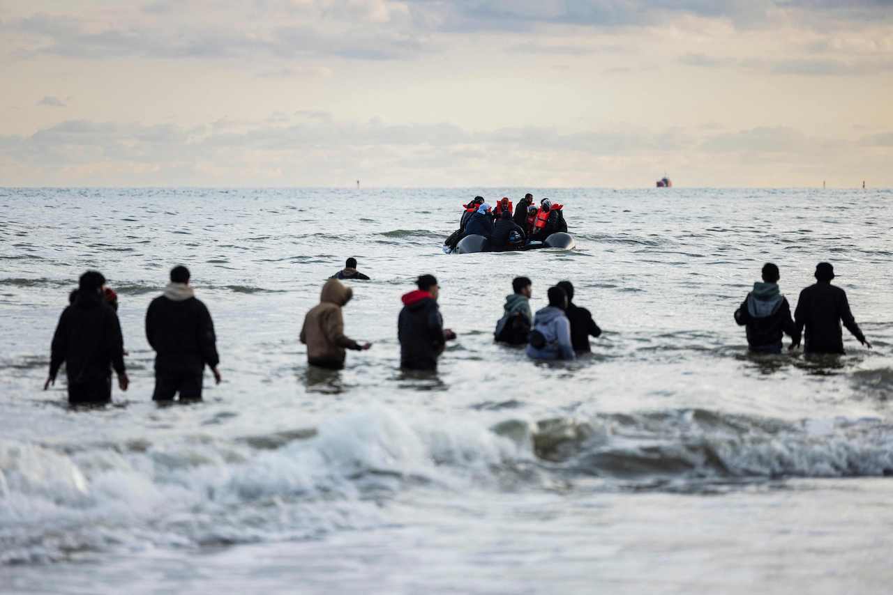 Migrants walks in the water to board a smuggler's boat on the beach of Gravelines, near Dunkirk, northern France on April 26, 2024, in an attempt to cross the English Channel. (AFP)