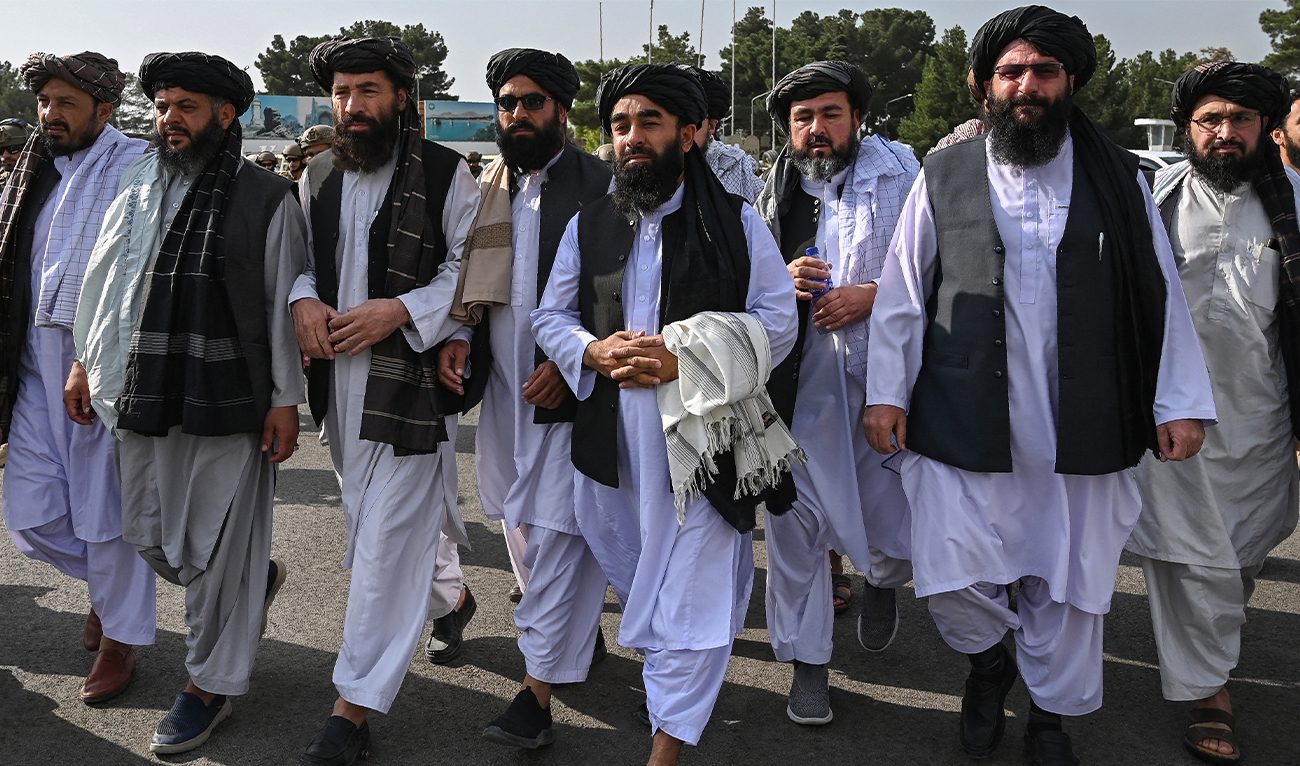 Taliban spokesman Zabihullah Mujahid (C, holding shawl) arrives as he is accompanied by officials to address a media conference at the airport in Kabul on August 31, 2021. (AFP/File)
