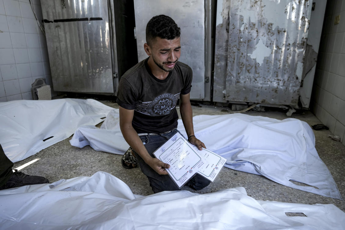 A Palestinian man mourns his 4-day-old twin relatives, killed in the Israeli bombardment of the Gaza Strip, as he holds their birth certificates, at a hospital morgue in Deir Al-Balah on Aug. 13, 2024. (AP)