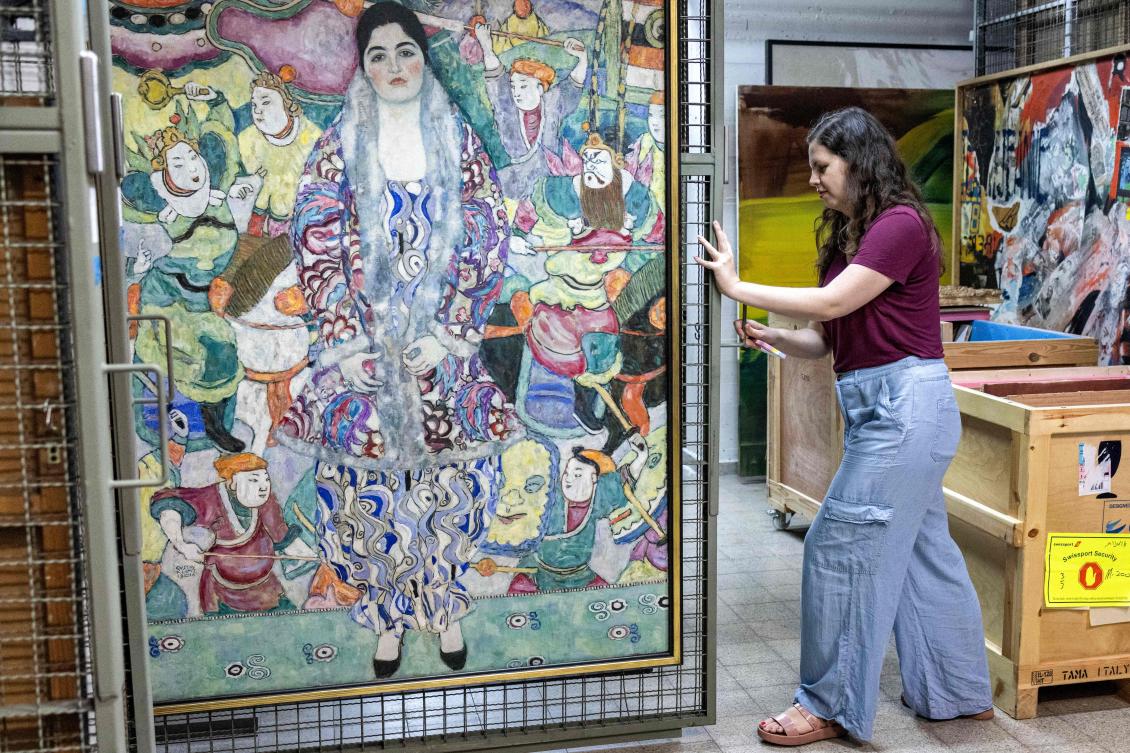 Nathalie Andrijasevic, an assistant curator at the Tel Aviv Museum of Art, handles a painting by Austrian painter Gustav Klimt which was moved to an underground safe room at the museum in Tel Aviv on Aug. 13, 2024. (AFP)