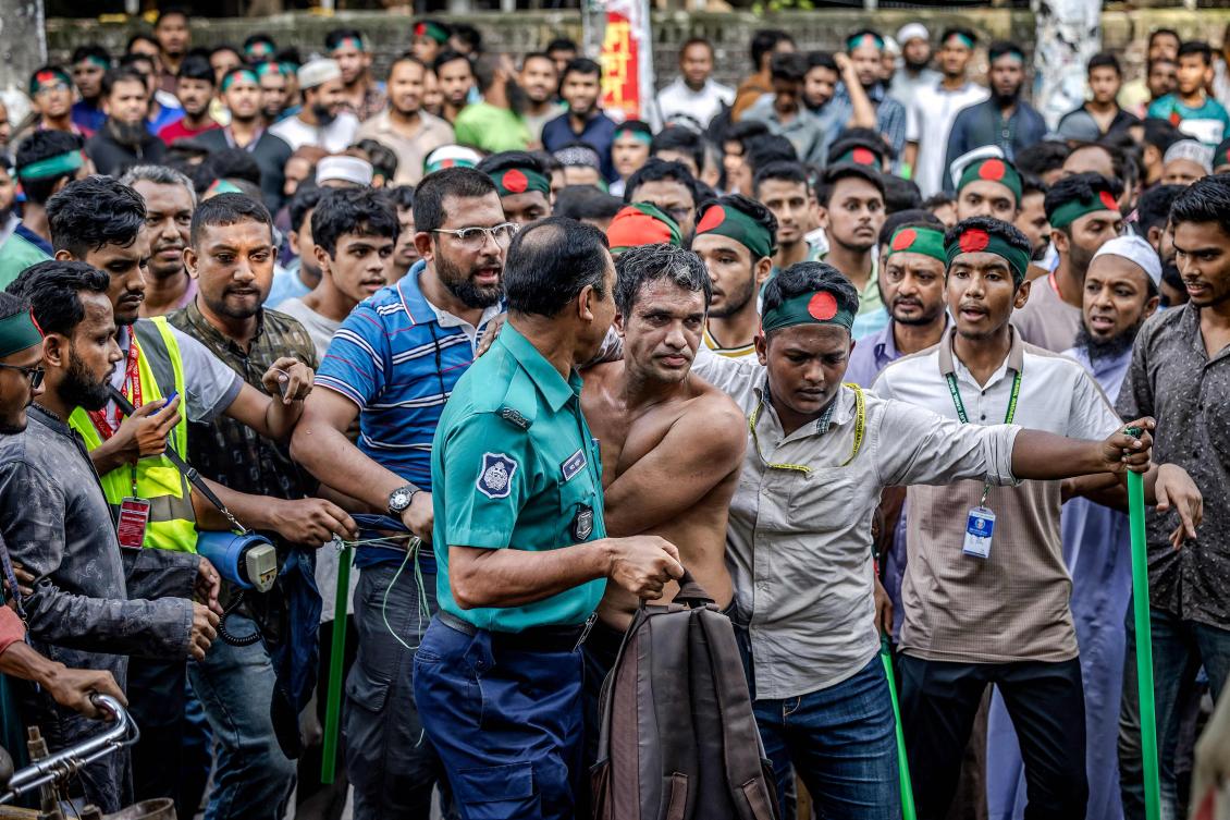Protesters surround a suspected sympathizer of ousted ex-premier Sheikh Hasina, near the house of her father Sheikh Mujibur Rahman, the first president of independent Bangladesh, in Dhaka on August 15, 2024. (AFP)