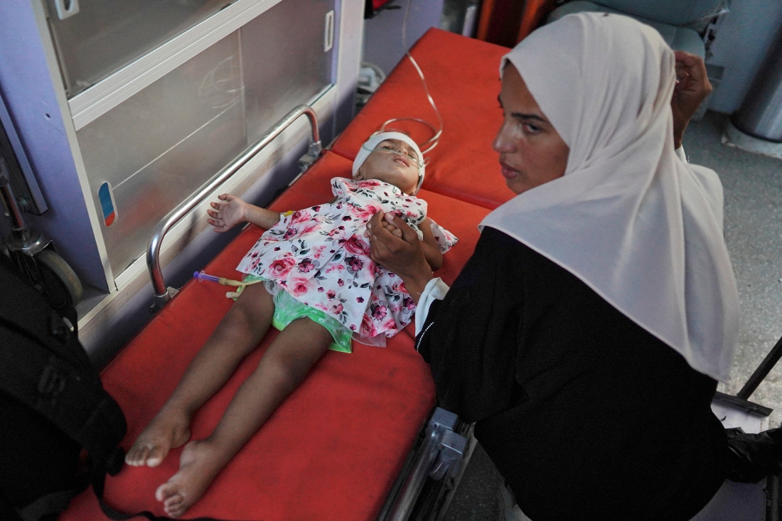 A woman sits next to her child in an ambulance at Al-Nasser hospital in Khan Yunis, after Israeli authorities gave permission for 11 children suffering from cancer to leave Gaza through the Kerem Shalom crossing. (FILE/AFP)