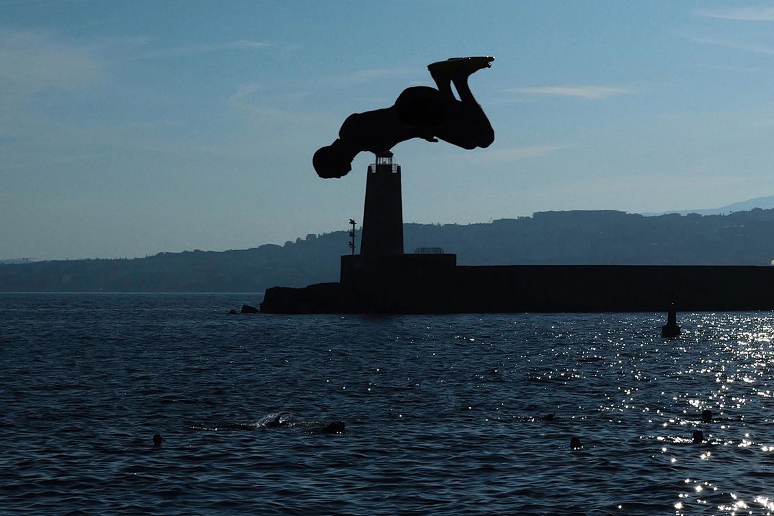 A youth is silhouetted as he dives into the Mediterranean sea on the French riviera city of Nice, on August 11, 2024. (AFP)