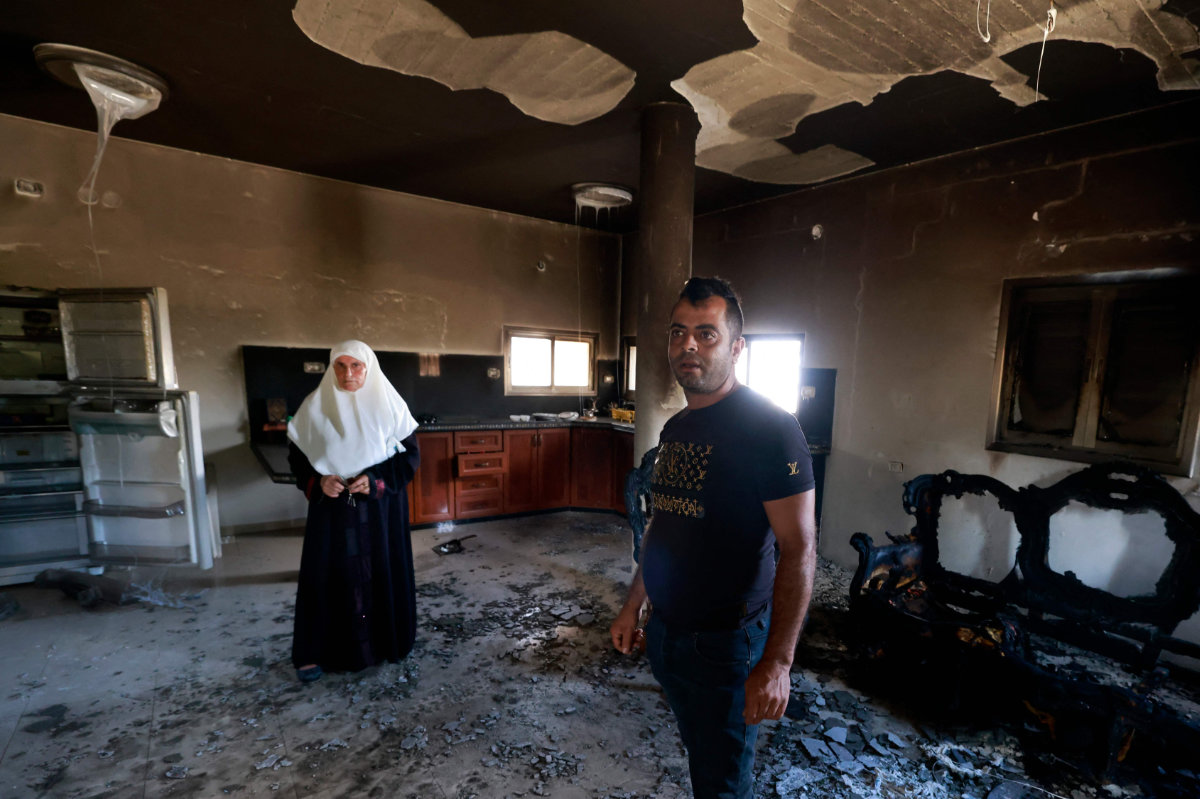 People stand inside their damaged home on Saturday, a day after an attack by Jewish settlers on the village of Jit near Nablus in the occupied West Bank that left a 23-year-old man dead and others with critical gunshot wounds. (AFP)