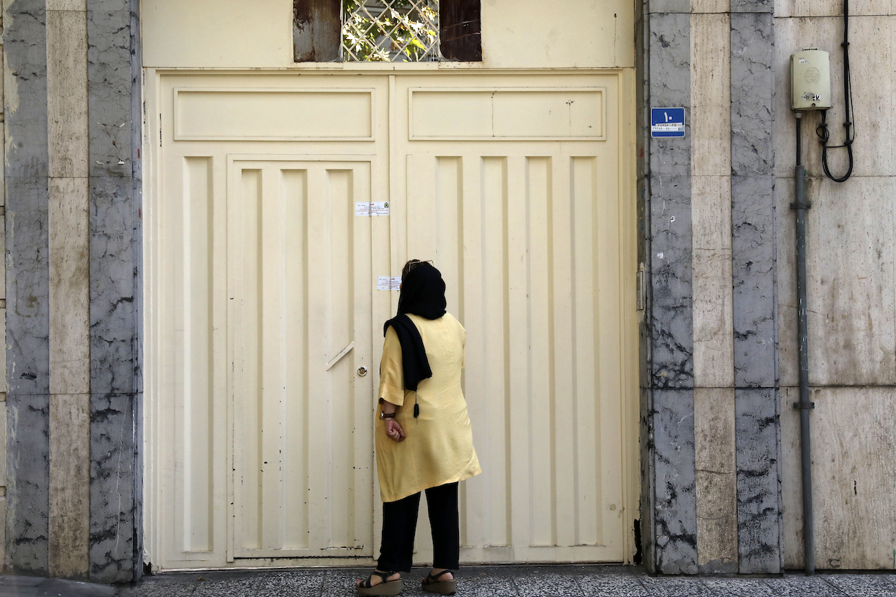 A woman reads the Iranian police closure notice on the gate of a language institute certified by German embassy, in Tehran, Iran, Tuesday, Aug. 20, 2024. (AP)