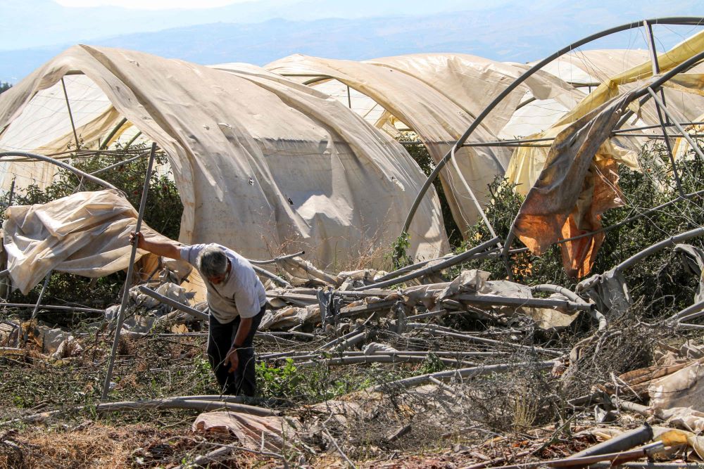 A man salvages the remains of a destroyed greenhouse after the overnight Israeli bombardment of Sarein, in the Bekaa valley, Lebanon, Aug. 20, 2024. (AFP)