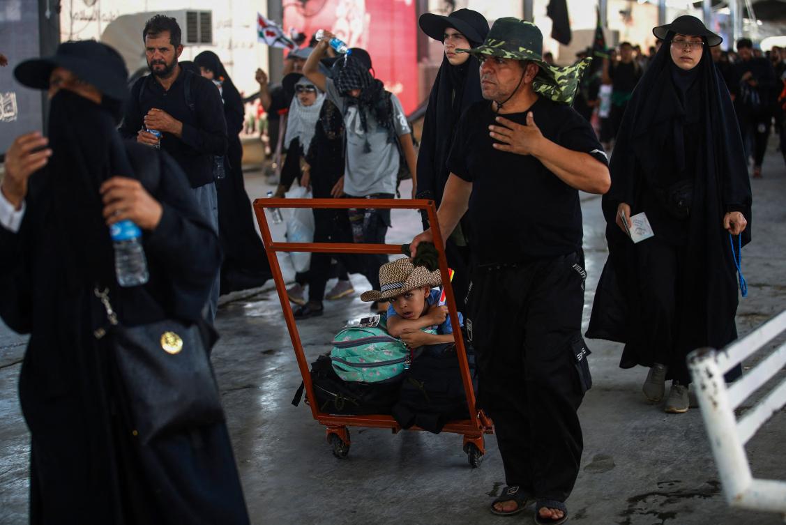 Shiite pilgrims arriving from Iran walk at the Zurbatiyah border crossing in Iraq's Wasit governorate on August 18, 2024 on their way to the shrine city of Karbala ahead of the Arbaeen commemorations that mark the end of a 40-day mourning period for the seventh century killing of Islam's Prophet Mohamed's grandson Imam Hussein Bin Ali. (AFP)