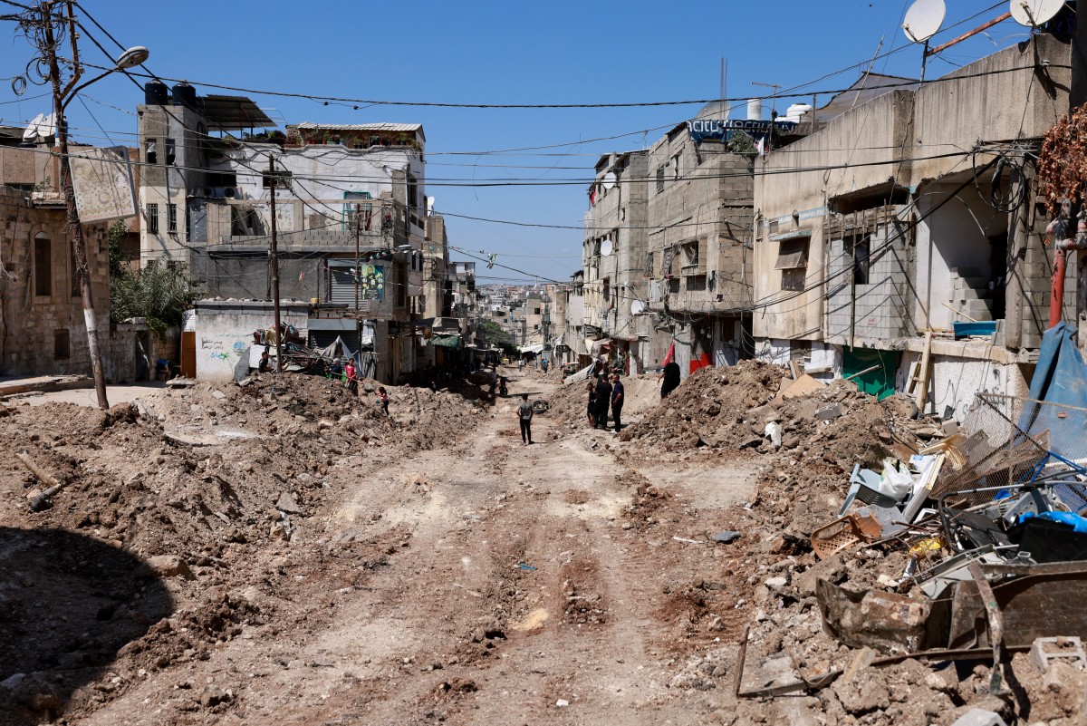 Palestinians inspect a damaged road following an Israeli army raid in Tulkarem, in the occupied West Bank (AFP)