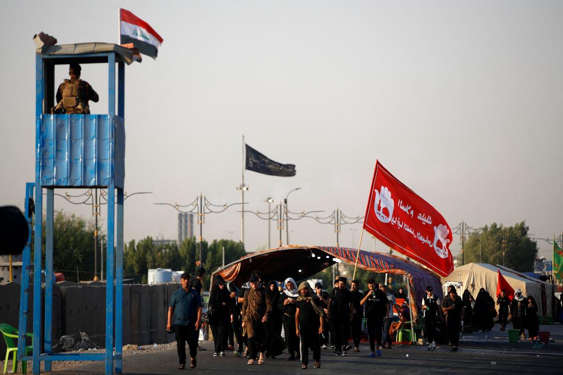 A member of the Iraqi security forces stands guard as Shiite Muslim pilgrims walk near Baghdad on August 21, 2024, on their way to Karbala (AFP)