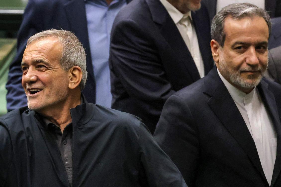 Iran's President Masoud Pezeshkian (L) reacts next to his nominee for the foreign ministry cabinet position Abbas Araghchi (R) as the former greets parliament members after giving an address during a session to approve his new cabinet appointments in Tehran. (File/AFP)
