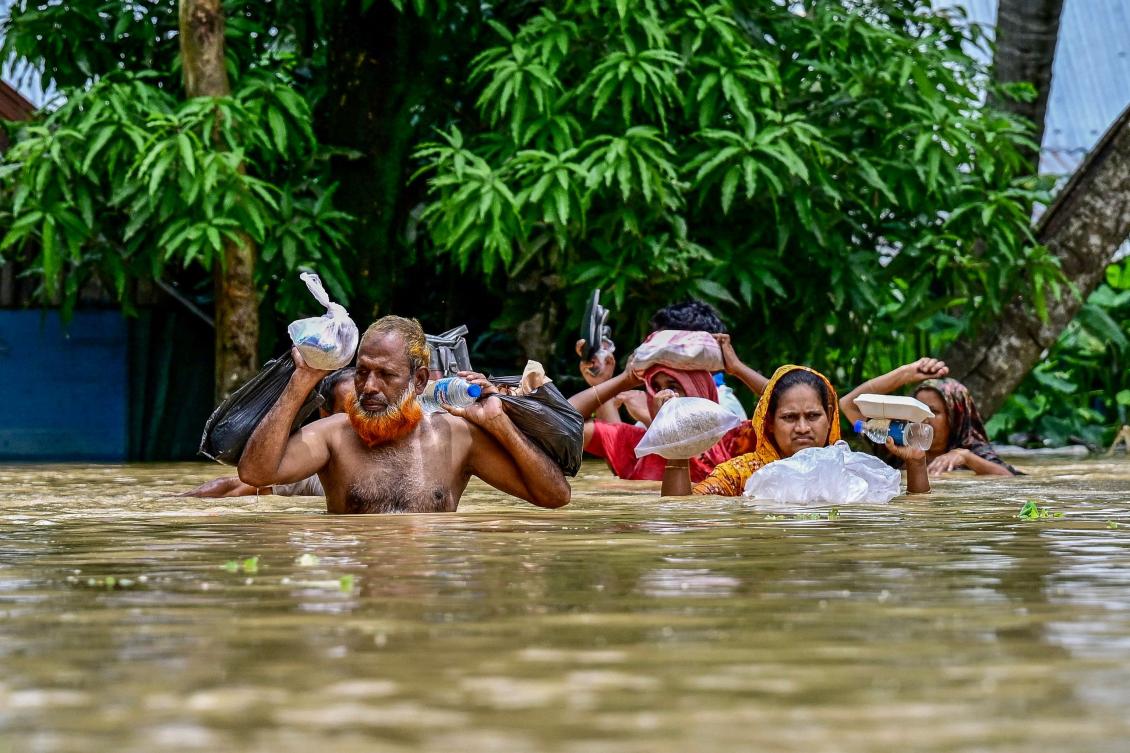 People carrying relief materials wade through flood waters in Feni, in south-eastern Bangladesh, on August 24, 2024.(AFP)
