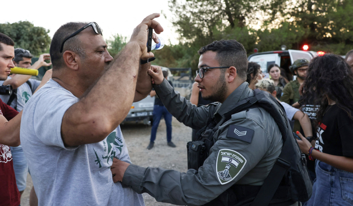 An Israeli border policeman pushes an activist as activists confront settlers in the occupied West Bank near Beit Jala village. (AFP)