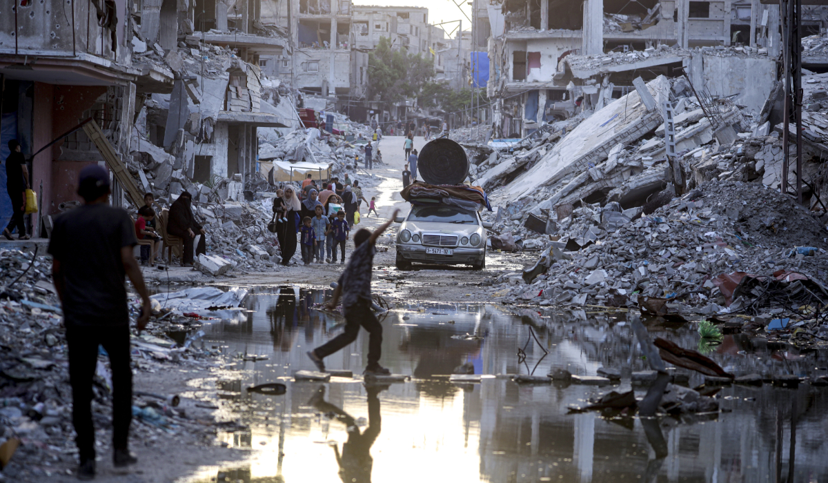 Palestinians displaced by the Israeli air and ground offensive on the Gaza Strip, walk past sewage flowing into the streets of the southern town of Khan Younis, Gaza Strip, on July 4, 2024. (AP)