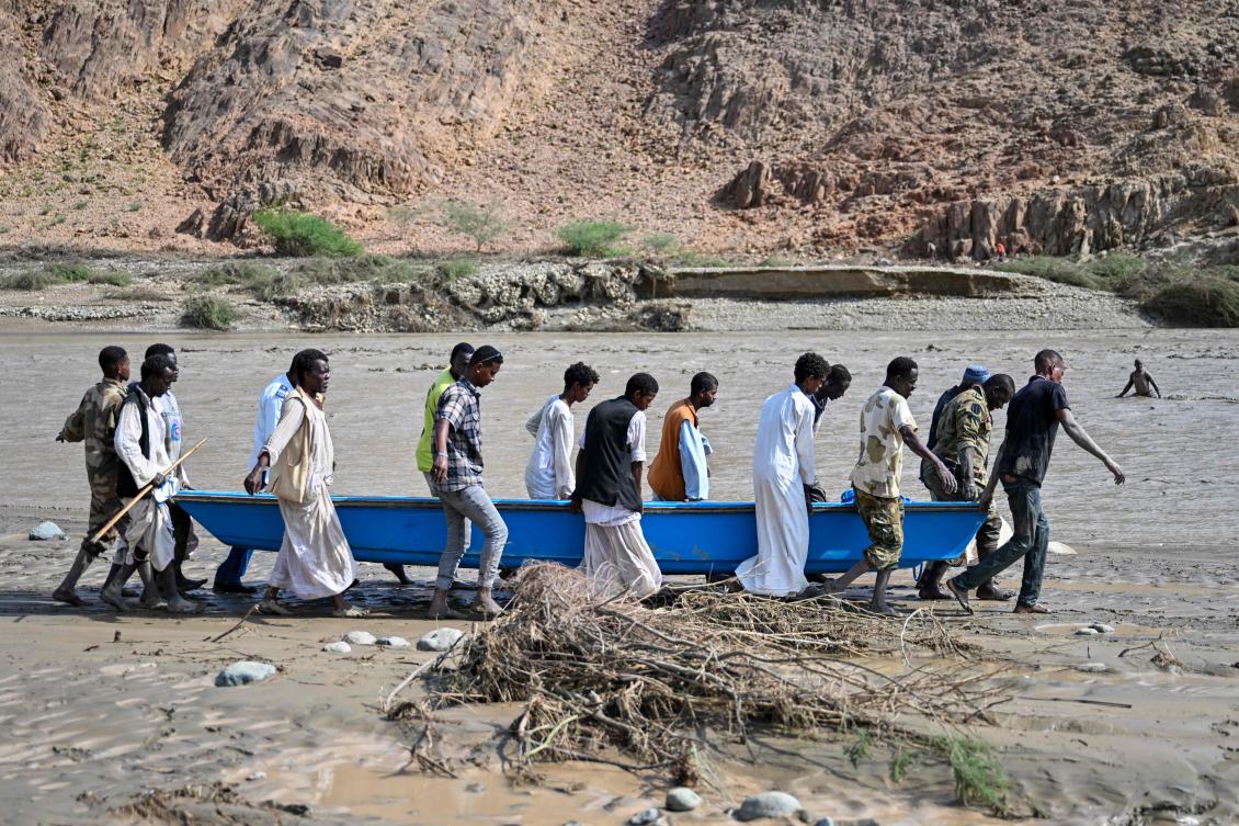 People carry a boat in muddy waters after the collapse of the Arbaat Dam, 40km north of Port Sudan following heavy rains and torrential floods on August 25, 2024. (AFP)
