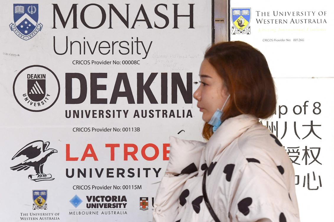 A woman walks past signage advertising Australian universities in Melbourne's central business district on June 10, 2020. (AFP)
