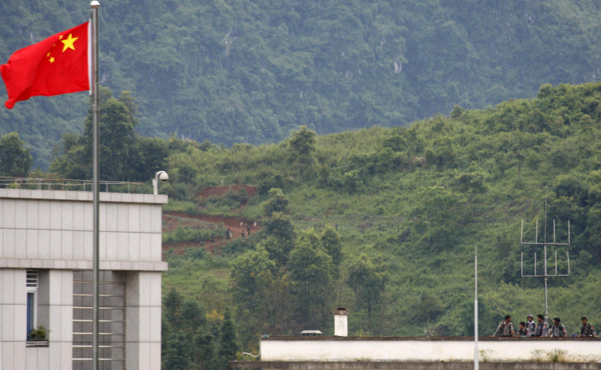 Above, Myanmar government troops stand on a rooftop on the Myanmar side, near a Chinese flag from the Chinese border town of Nansan in southwestern China’s Yunnan province. (AP)