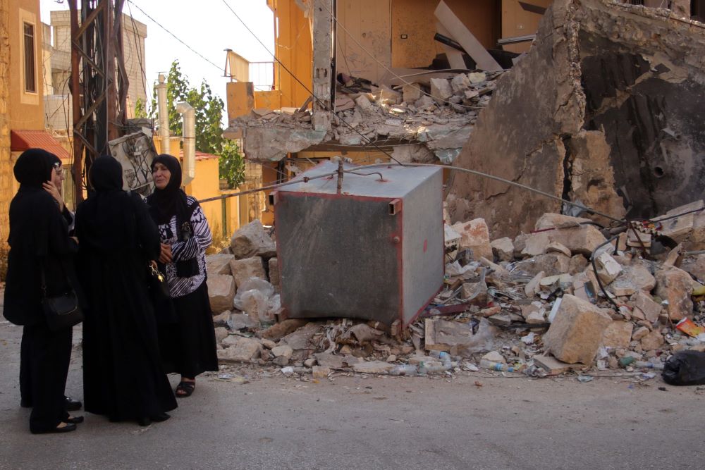 Mourners stand next to the rubble of a building, destroyed in an Israeli strike, after a funeral in the southern Lebanese village of Khiam on August 26, 2024. (AFP)