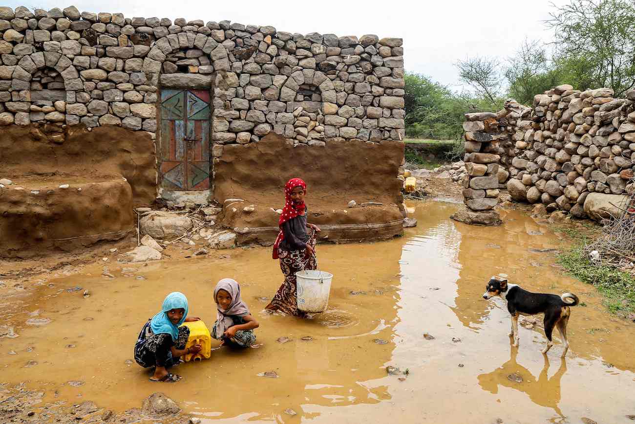 Children fill up a jerrycan from a water puddle left by recent heavy flooding in the Hays region, south of Hodeidah province, on August 28, 2024. (AFP)