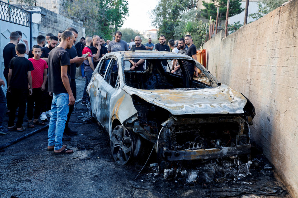Palestinians assess the damage at the scene of an Israeli strike on a car near Jenin in the Israeli-occupied West Bank. (File/Reuters)
