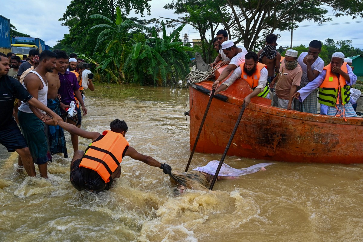 Volunteers and relief workers recover a dead body from the flood waters in Feni on August 25, 2024.(AFP)