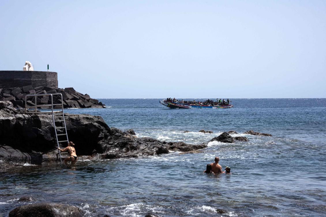 Swimmers watch as a ‘cayuco’ boat carrying African migrant people, part of a group of 386 migrants onboard of two boats, arrives at La Restinga port on the Canary island of El Hierro on August 28, 2024. (AFP)