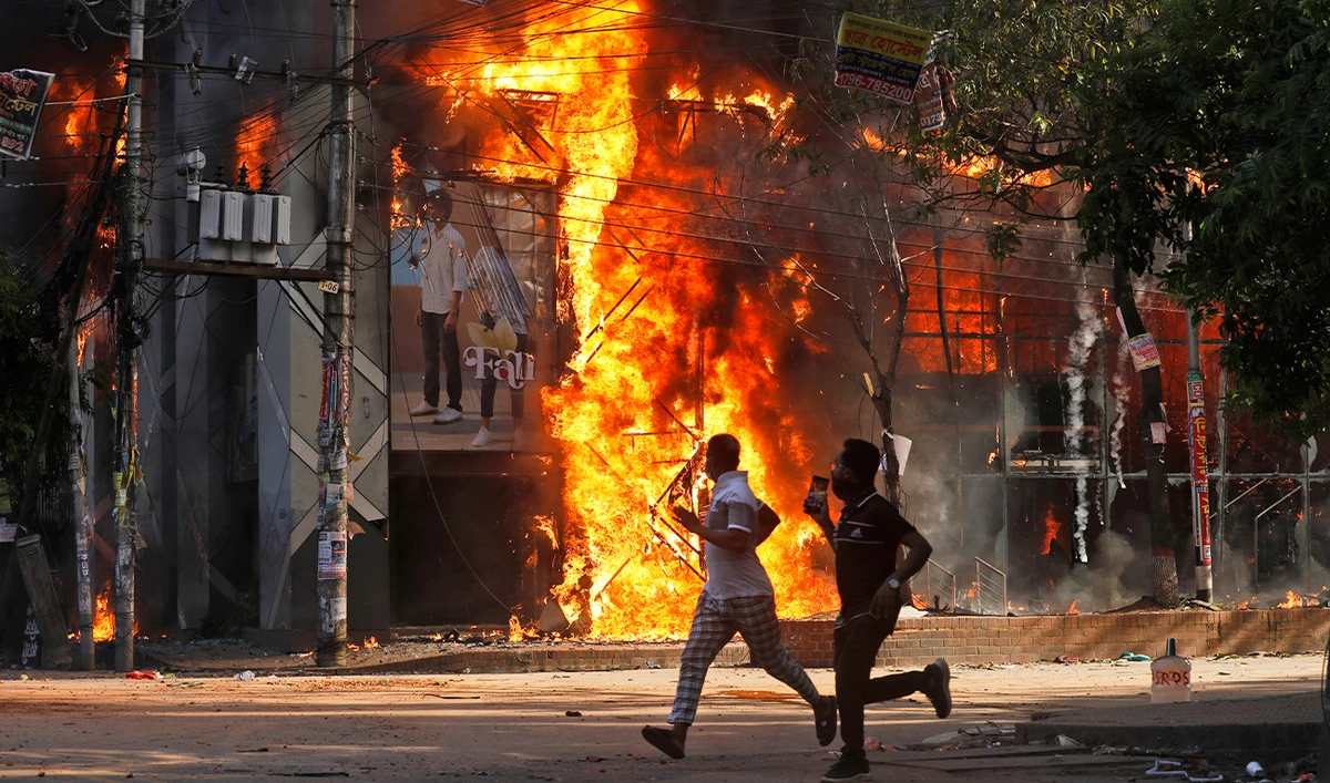 Men run past a shopping center which was set on fire by protesters during a rally against Prime Minister Sheikh Hasina and her government demanding justice for the victims killed in the recent countrywide deadly clashes, in Dhaka, Bangladesh, on August 4, 2024. (AP)