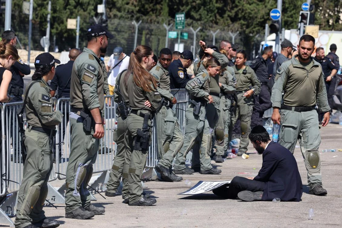 Ultra-Orthodox protester sits on the ground during a protest on the first day Ultra-Orthodox Jewish men were requested to enlist for compulsory military service, outside the Tel Hashomer army base near Tel Aviv, August 5, 2024. (AFP)