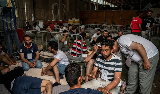 Survivors of a shipwreck sit inside a warehouse at the port in Kalamata town, on June 15, 2023, after a boat carrying migrants sank in international waters in the Ionian Sea. (AFP/File)