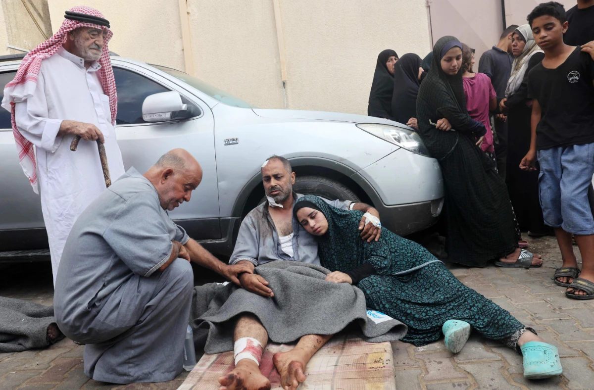 An injured man comforts his daughter after several members of his family were killed in an overnight Israeli strike that hit the family home in Nuseirat, in front of the Al-Aqsa Martyrs hospital in Deir el-Balah in the central Gaza Strip on August 10, 2024, amid the ongoing conflict between Israel and the Palestinian Hamas movement. (AFP)