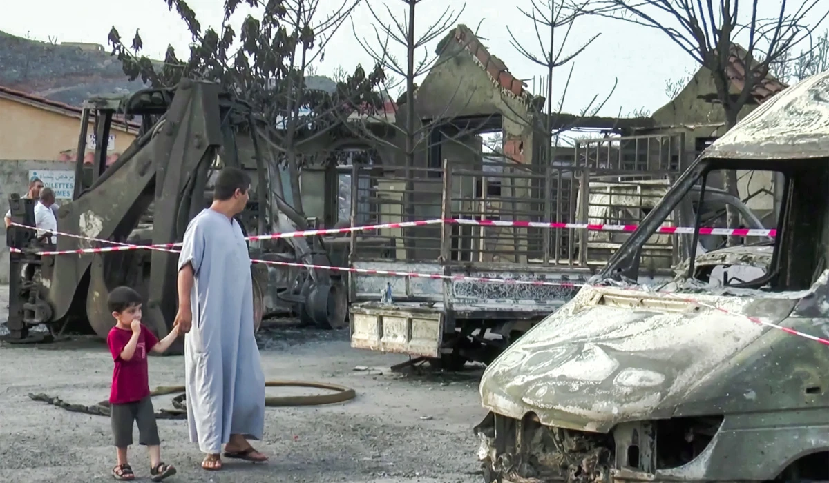 A man and a child inspecting damage to burnt vehicles and buildings in the village of Tighramt in the municipality of Bani Kusayla in Bejaia province of northern Algeria on July 25, 2023. (AFP file photo)