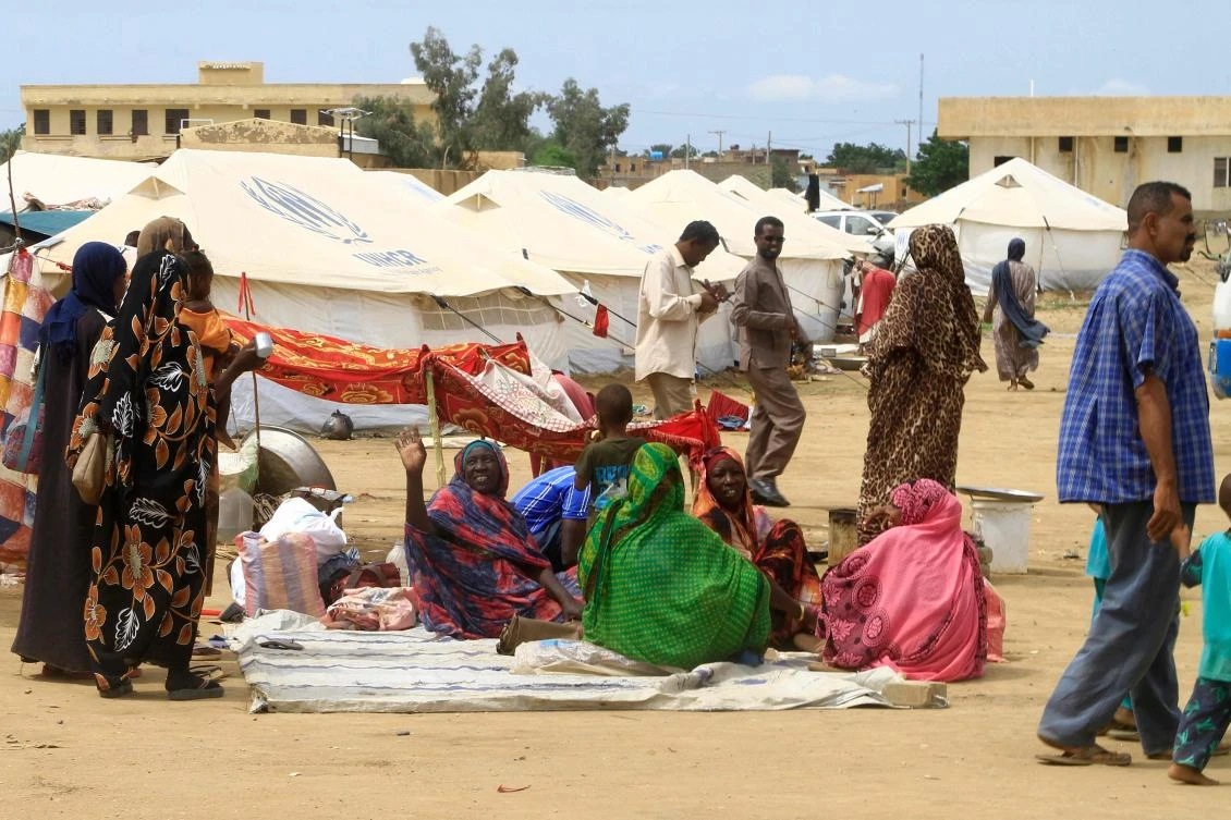 Sudanese already displaced by conflict, walk near tents at a makeshift campsite they were evacuated to following deadly floods in the eastern city of Kassala on Aug. 12, 2024. (AFP)