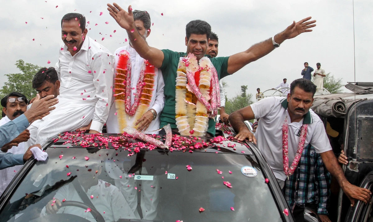 Arshad Nadeem (C), Pakistan's javelin gold medalist at the Paris 2024 Olympic Games, waves to fans upon his arrival at his hometown in Mian Channu on Aug. 11, 2024. (AFP)